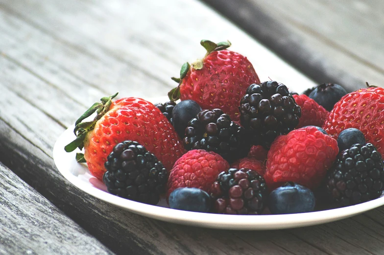 a bowl of berries sits on a table