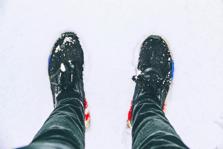 a person standing in the snow in black shoes