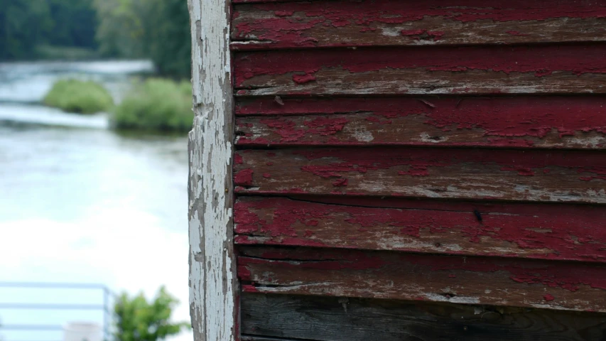 the door to a red and white wood structure by a river