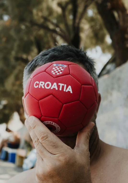 a man holding a soccer ball up to his face