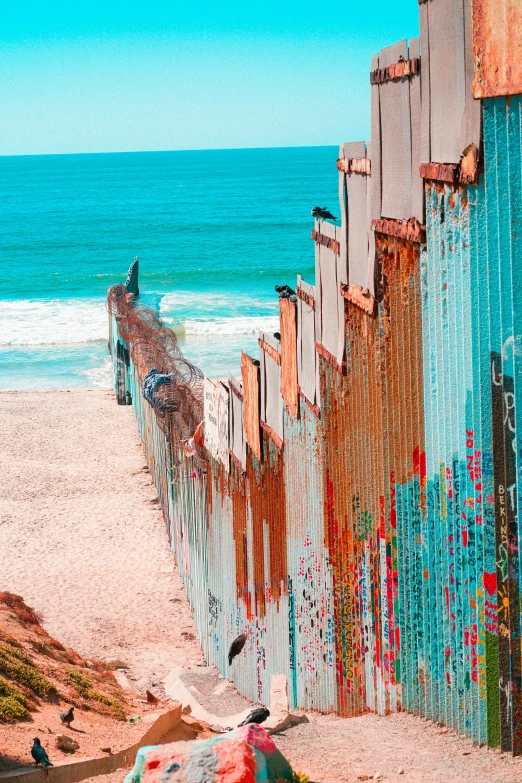 a very colorful fence along the beach by the water