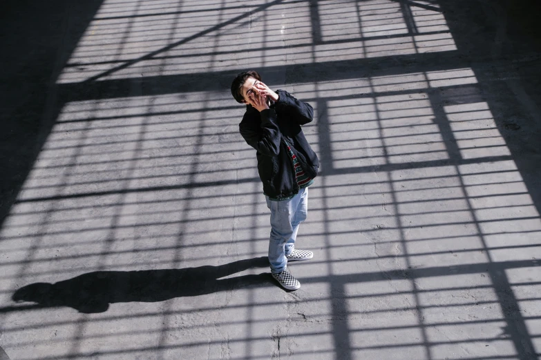 a man standing in the shadow on the ground using a cell phone