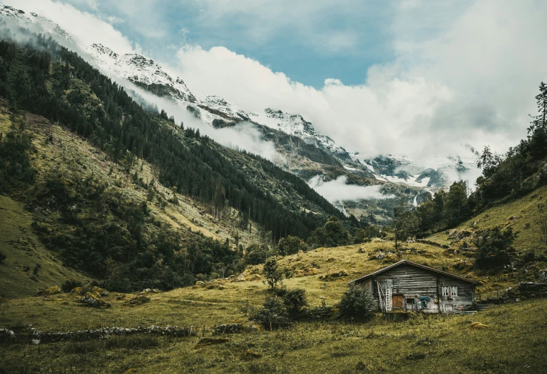 two small cabins in a lush green valley with low mountains in the background