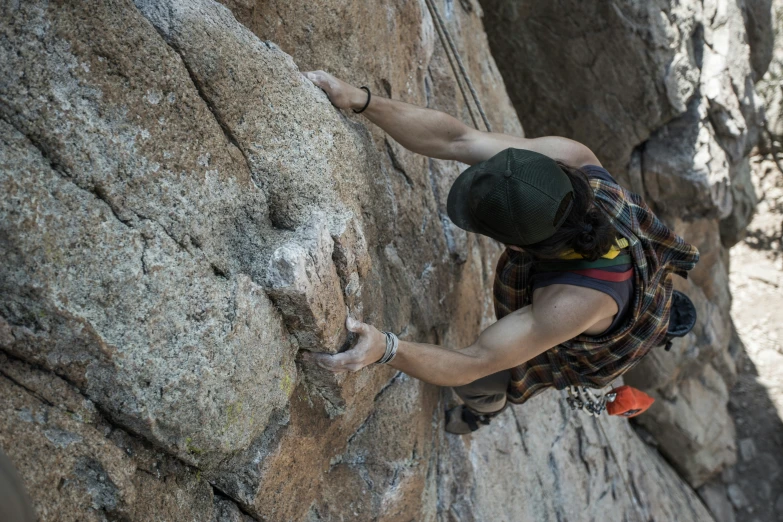 man climbing up a steep rock face and reaching down