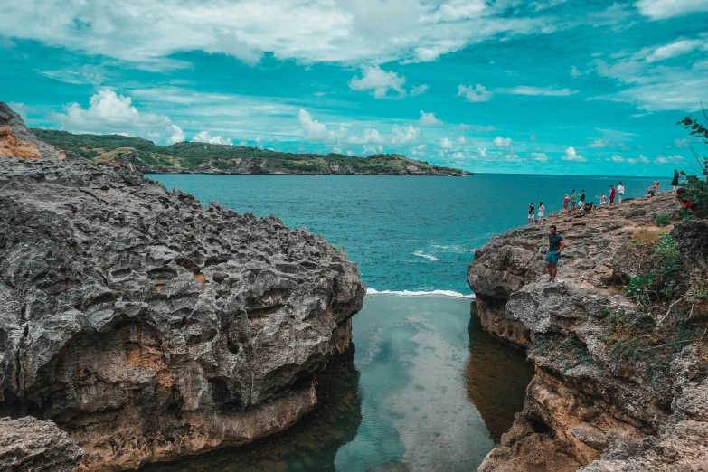 people are standing on a cliff overlooking the water