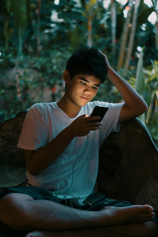 a man is sitting on a bench and using his cell phone