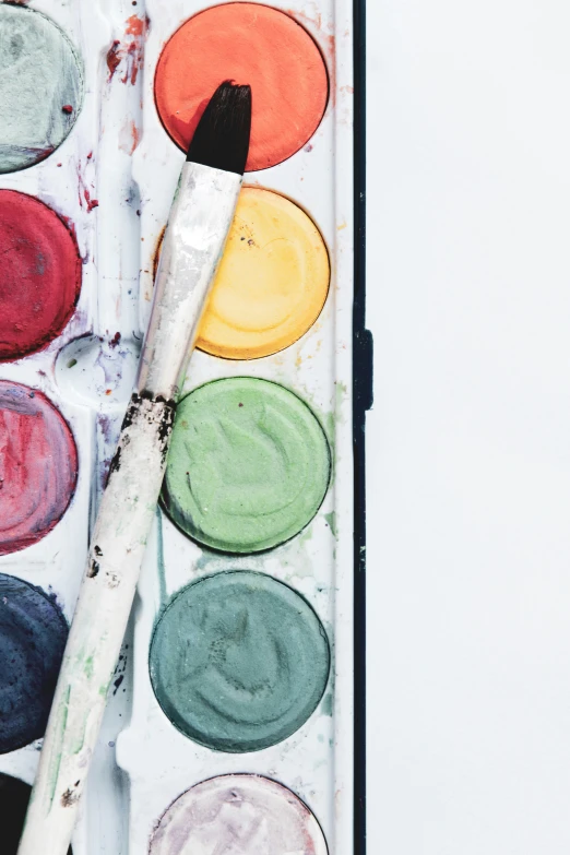 a water color palette and a brush sitting on a paint tray