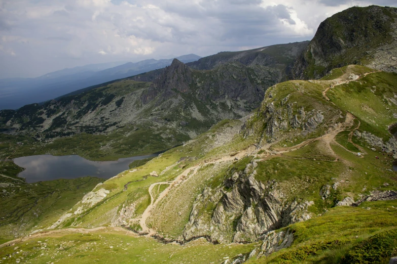 a dirt path on the side of a steep green hillside