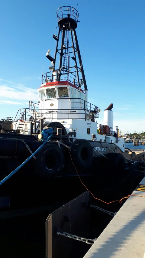 large tug boat in dock next to white buoy