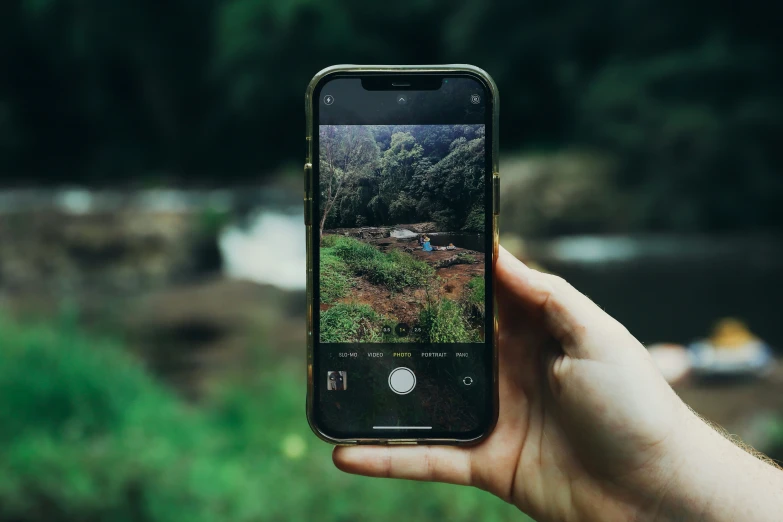 a person's hand holding an iphone with a landscape pograph taken