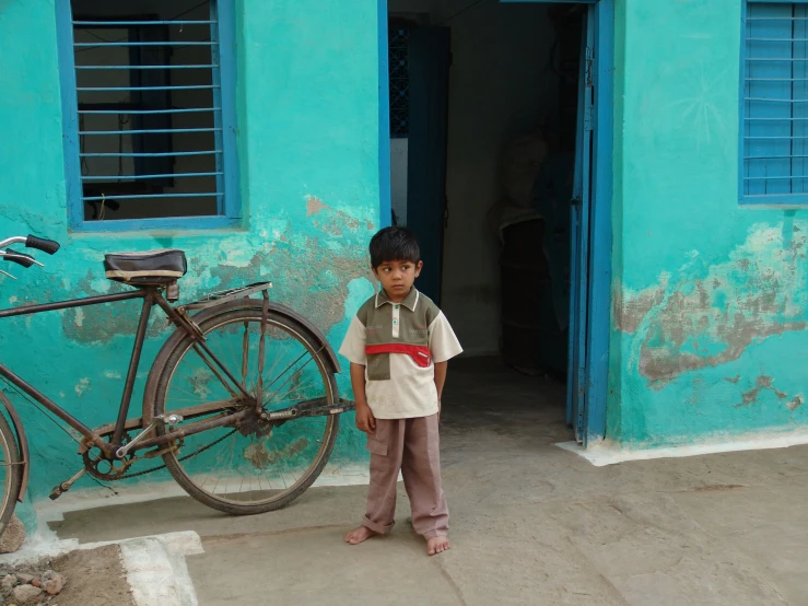 the boy stands in front of the entrance to his home