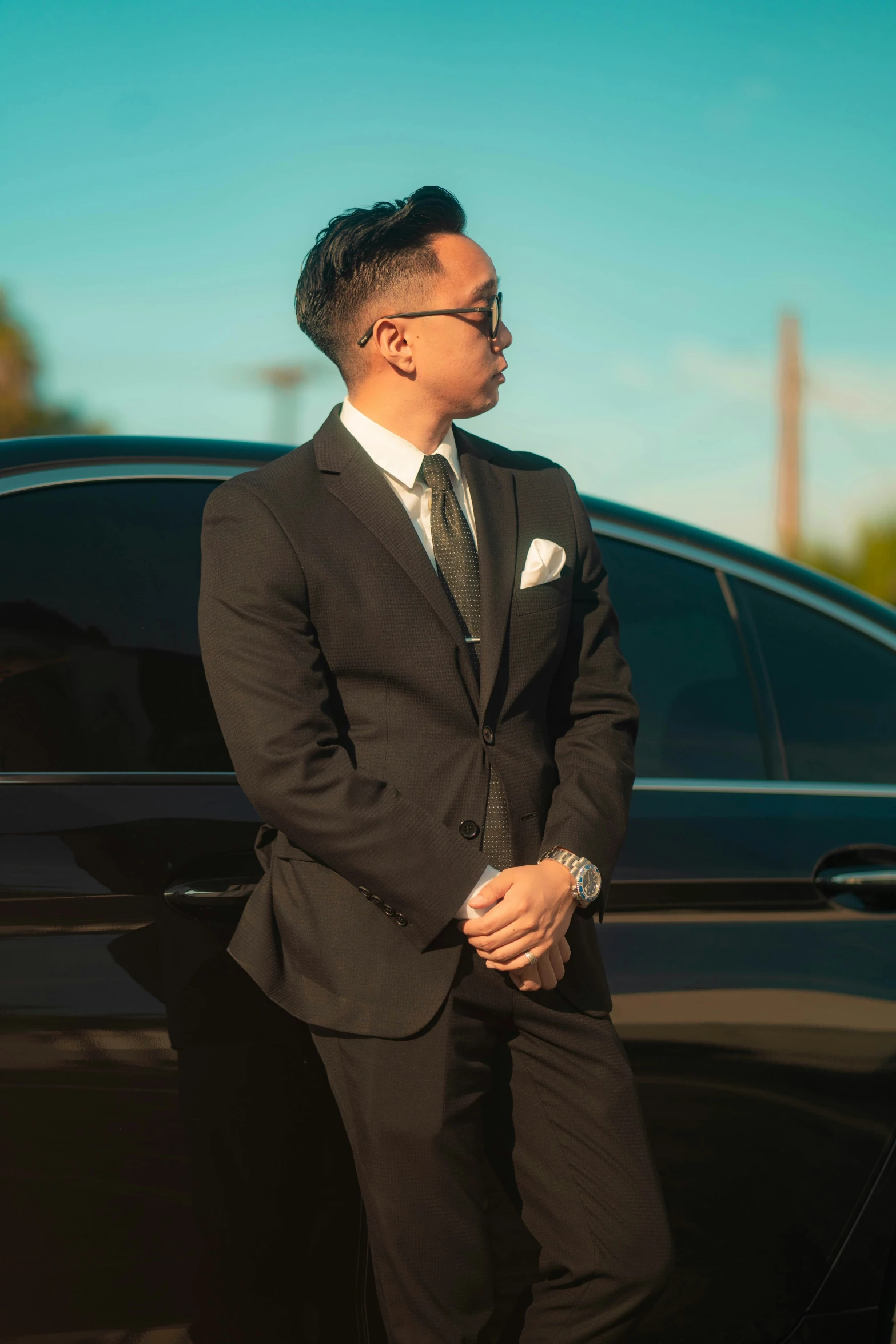 a young asian man leaning against a car