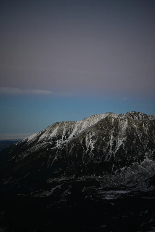 the snow capped mountains in this view have very dark and white hues