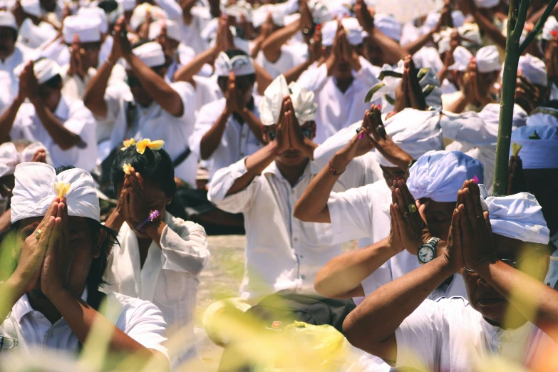 people in white are standing in the grass with their hands up