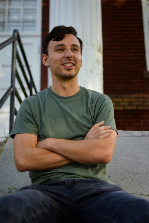 a man smiles brightly while sitting on the curb