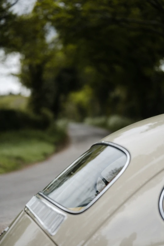 a car parked on a road, with an old fashioned rear end mirror