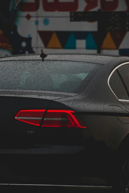 the tail light on a black car in front of some colorful patterns