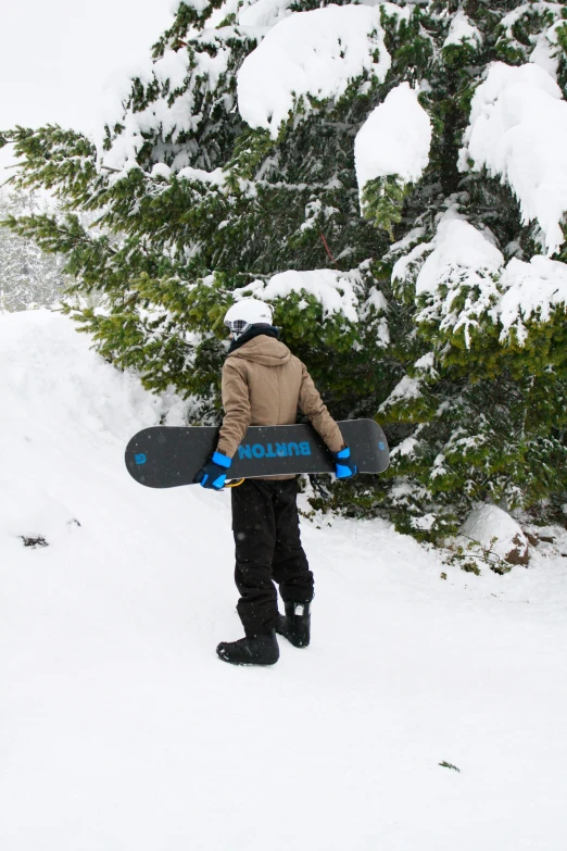 a man carrying a snowboard on his back while walking down a hill