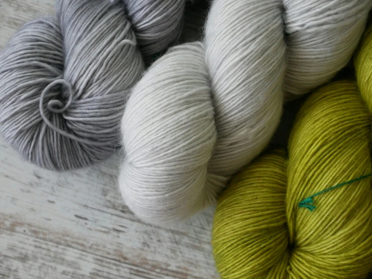 a table covered in different shades of grey and yellow yarn