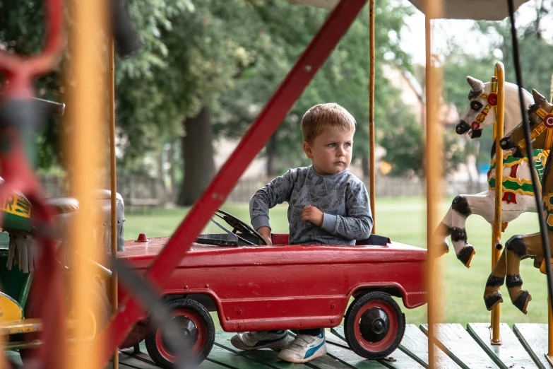 the small boy is driving his toy car