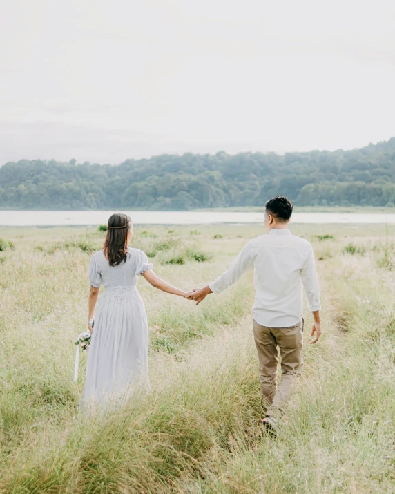 the bride and groom hold hands while walking through the tall grass