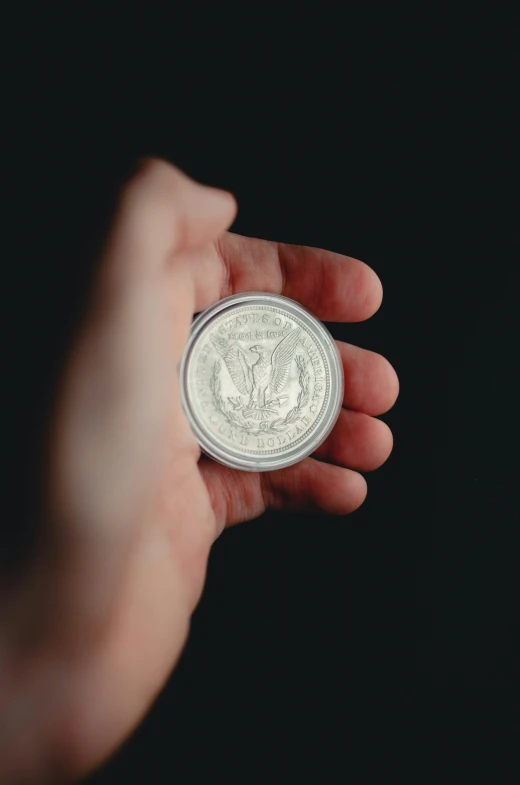 a man's hand holding a small white coin