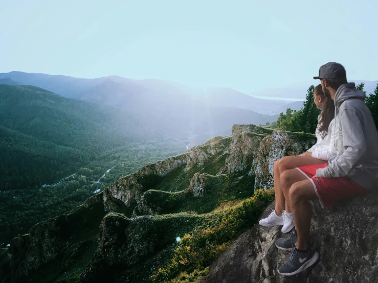 there is a man and woman talking on a mountain ledge