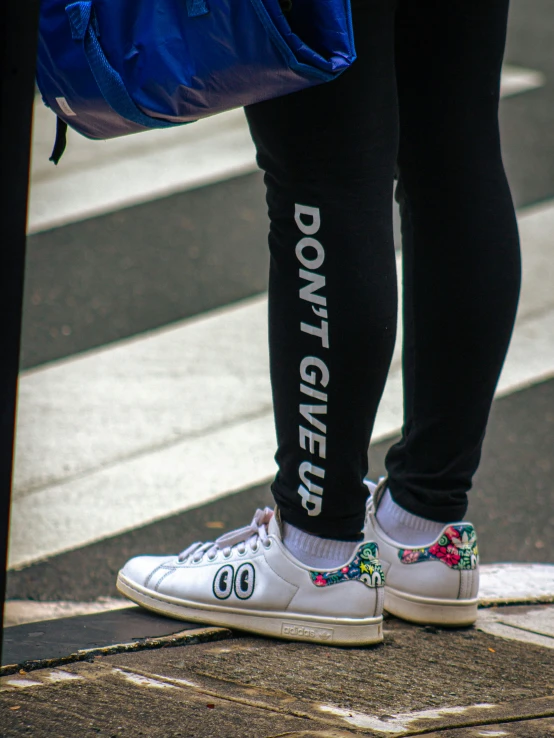 a person is walking along the side walk with some white sneakers