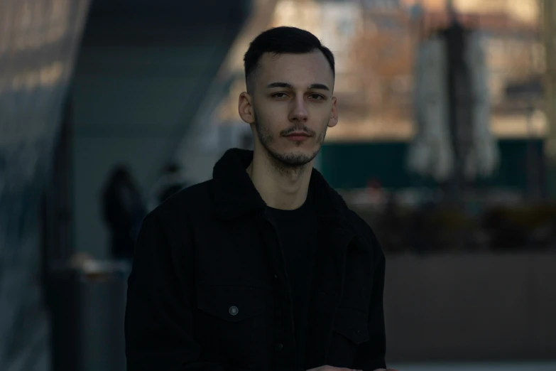 man standing on sidewalk near large building with dark jacket