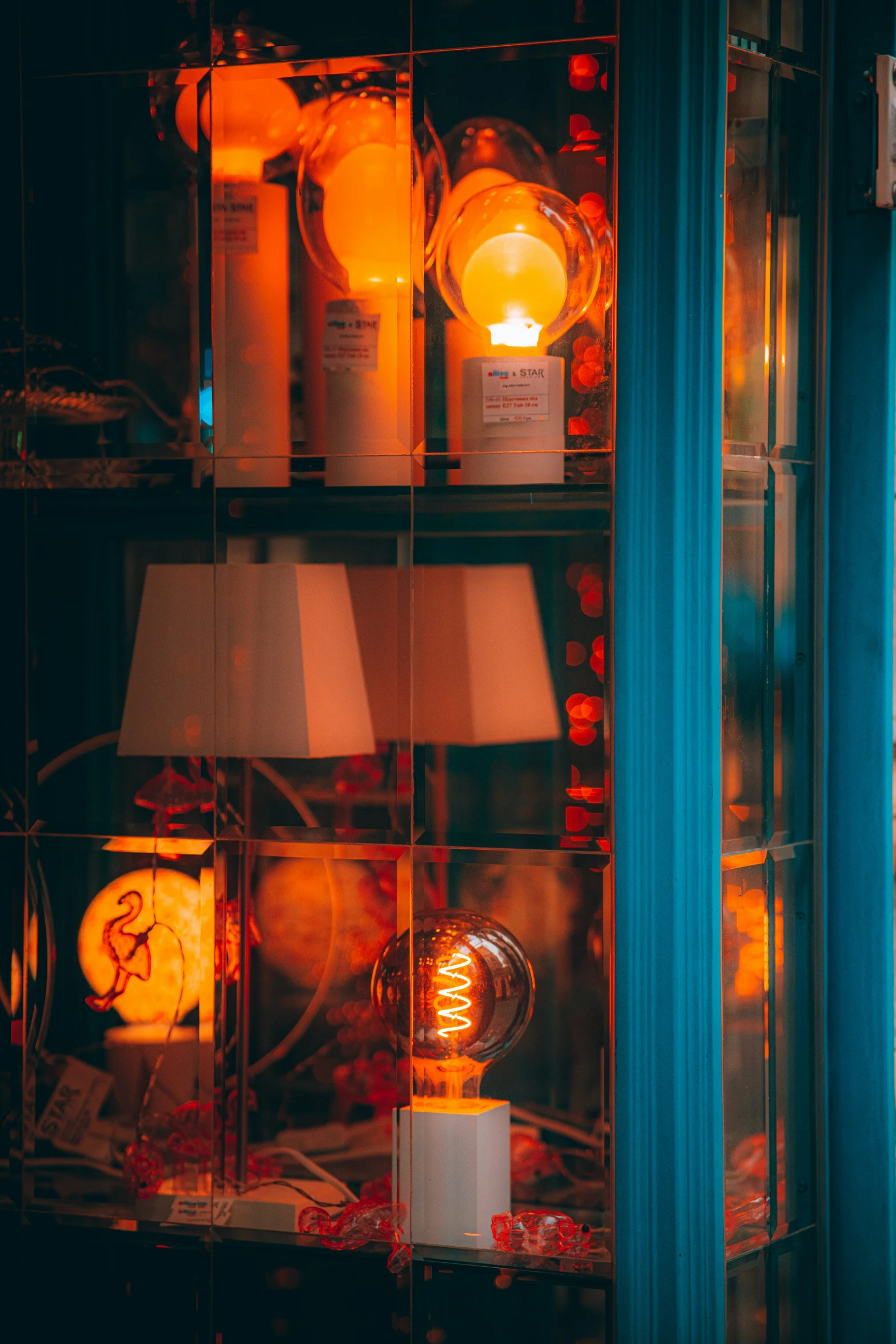 a lighted lamp sitting in the middle of an old fashioned shop window