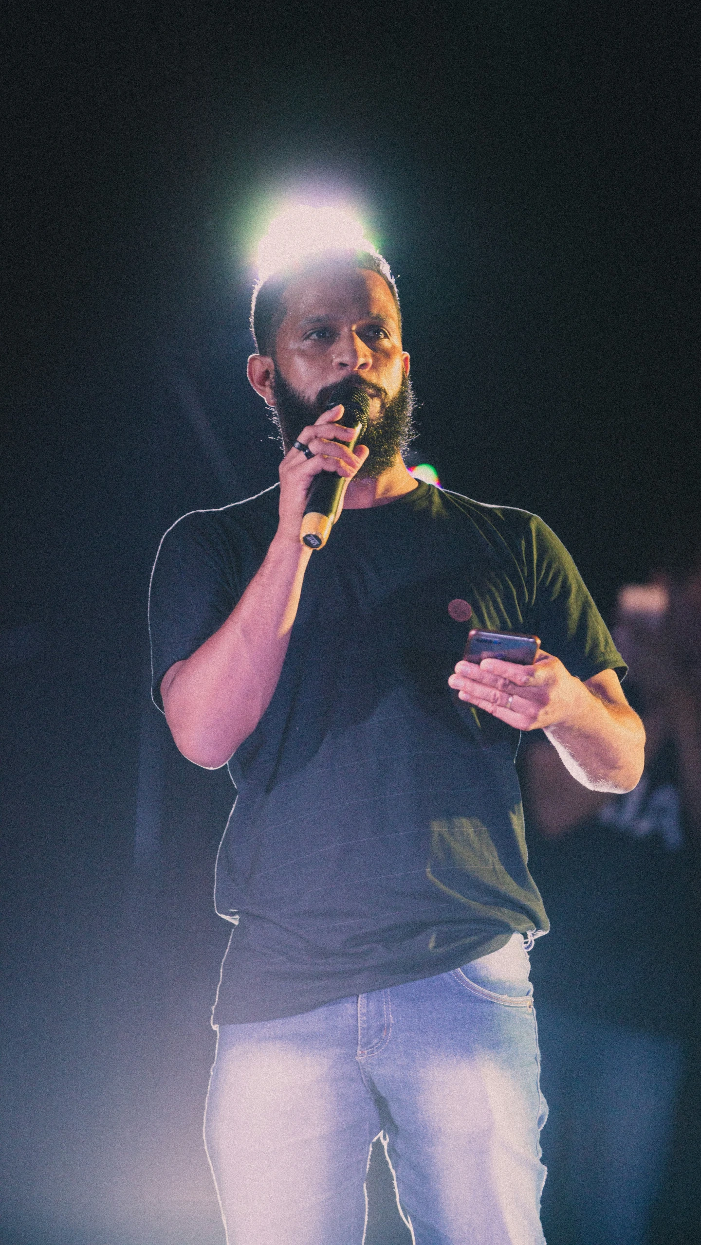 a man on a cell phone stands at the microphone