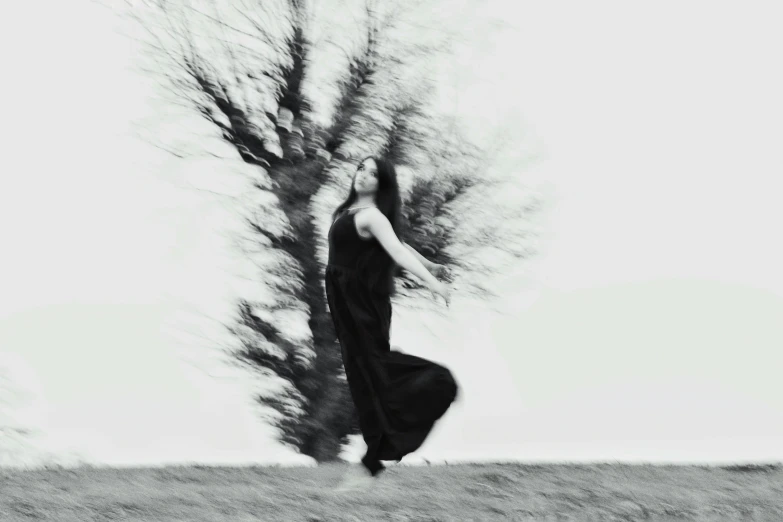 a person in a long black dress leaning on a tree