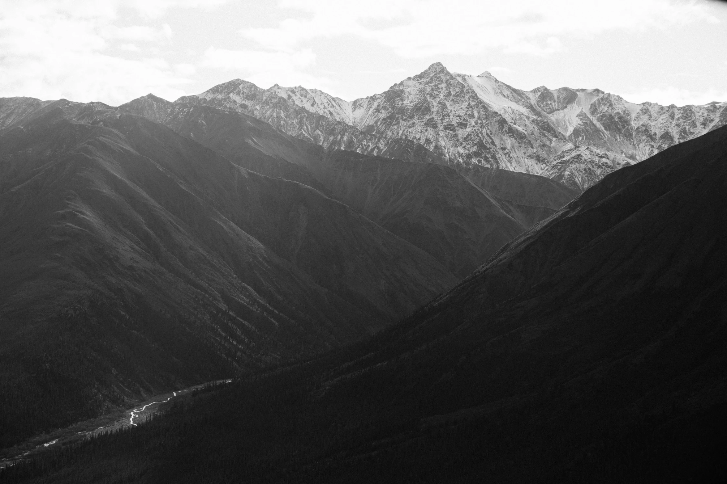 black and white pograph of mountains under cloudy skies