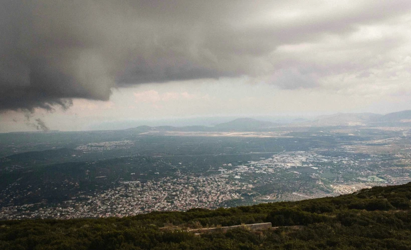 storm clouds above some trees and mountains on a cloudy day