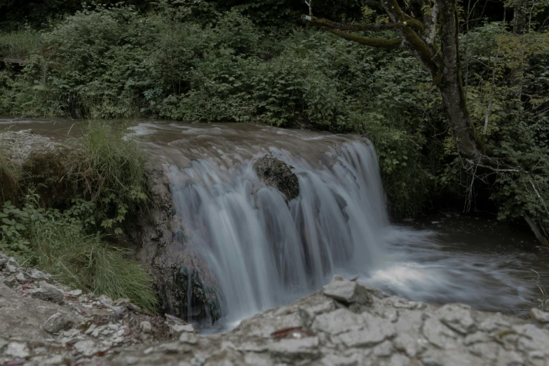 a waterfall surrounded by lush green trees and water