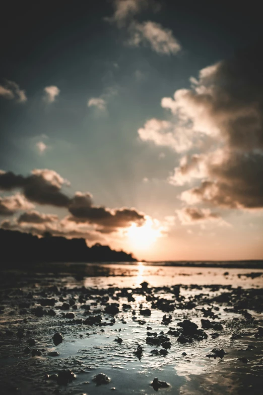 the sun setting over a ocean covered in sea glass