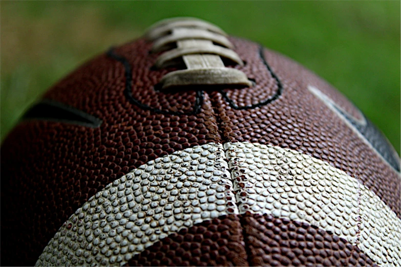 an old worn football laying on grass