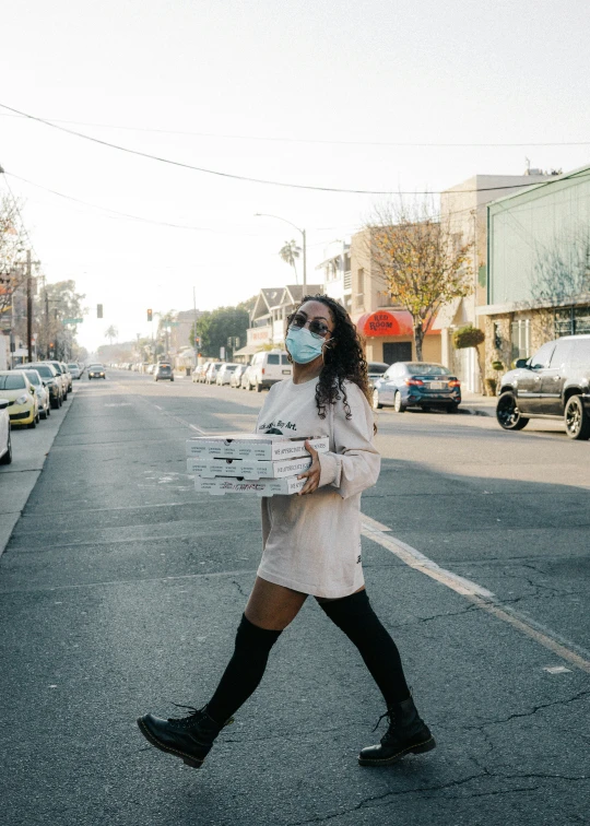 a woman is wearing a face mask as she walks down a street