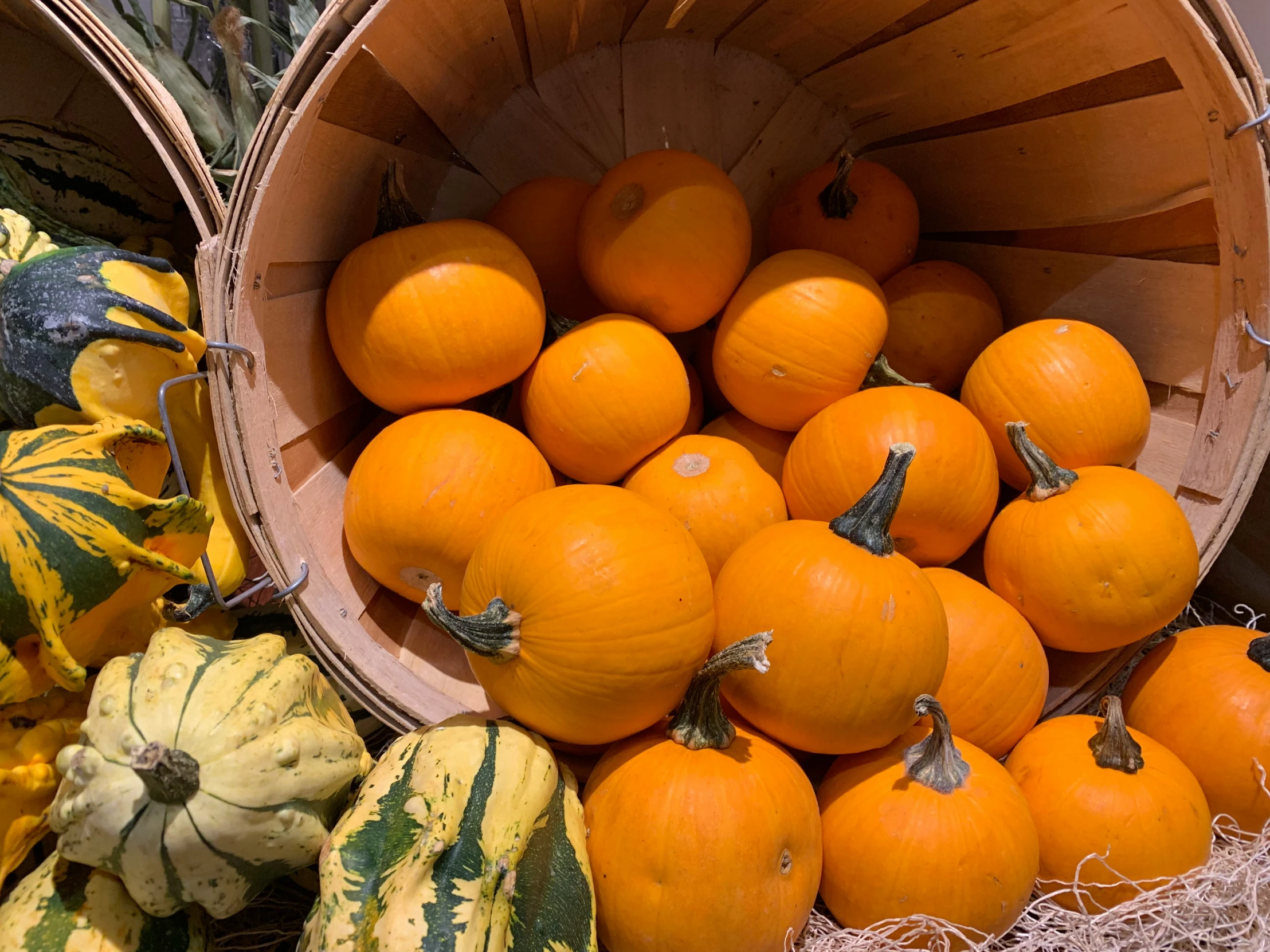 a wooden basket filled with oranges next to squash