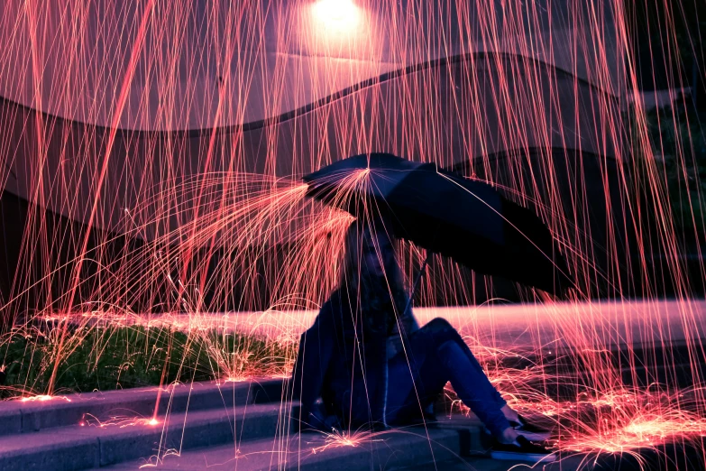 a person holding an umbrella sits under the stars