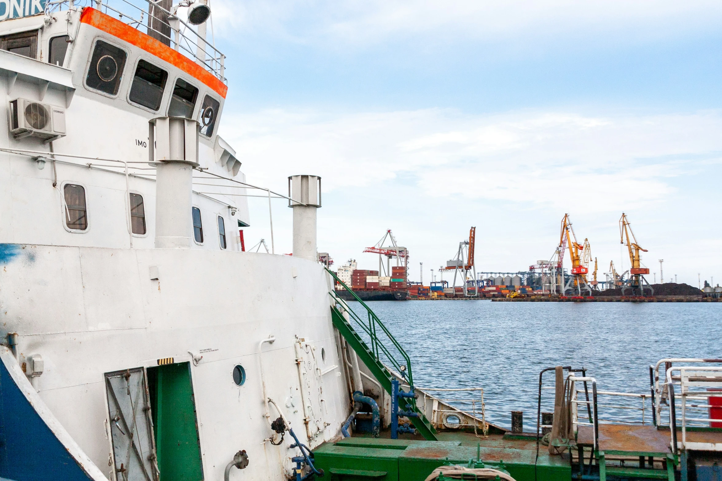 a boat docked at a dock with ships in the background