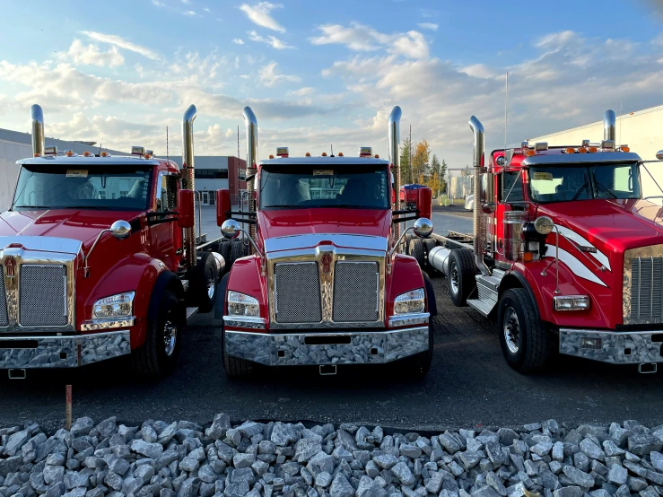 three big rig trucks in a row parked near rocks