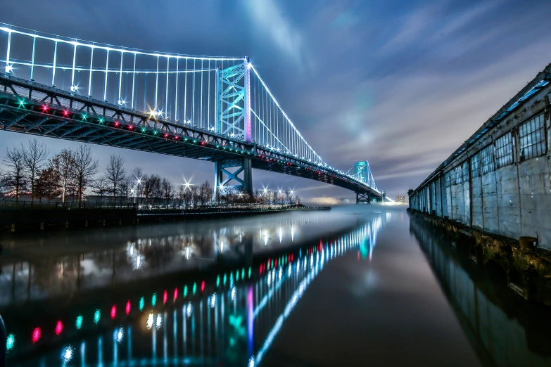 a night view of a bridge with lights on it and the water in front