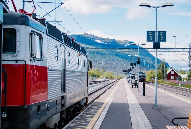 the red and white train is approaching a station