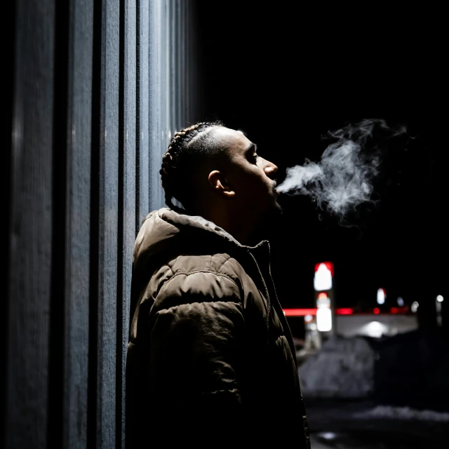 a man smoking his cigarette while standing in the dark