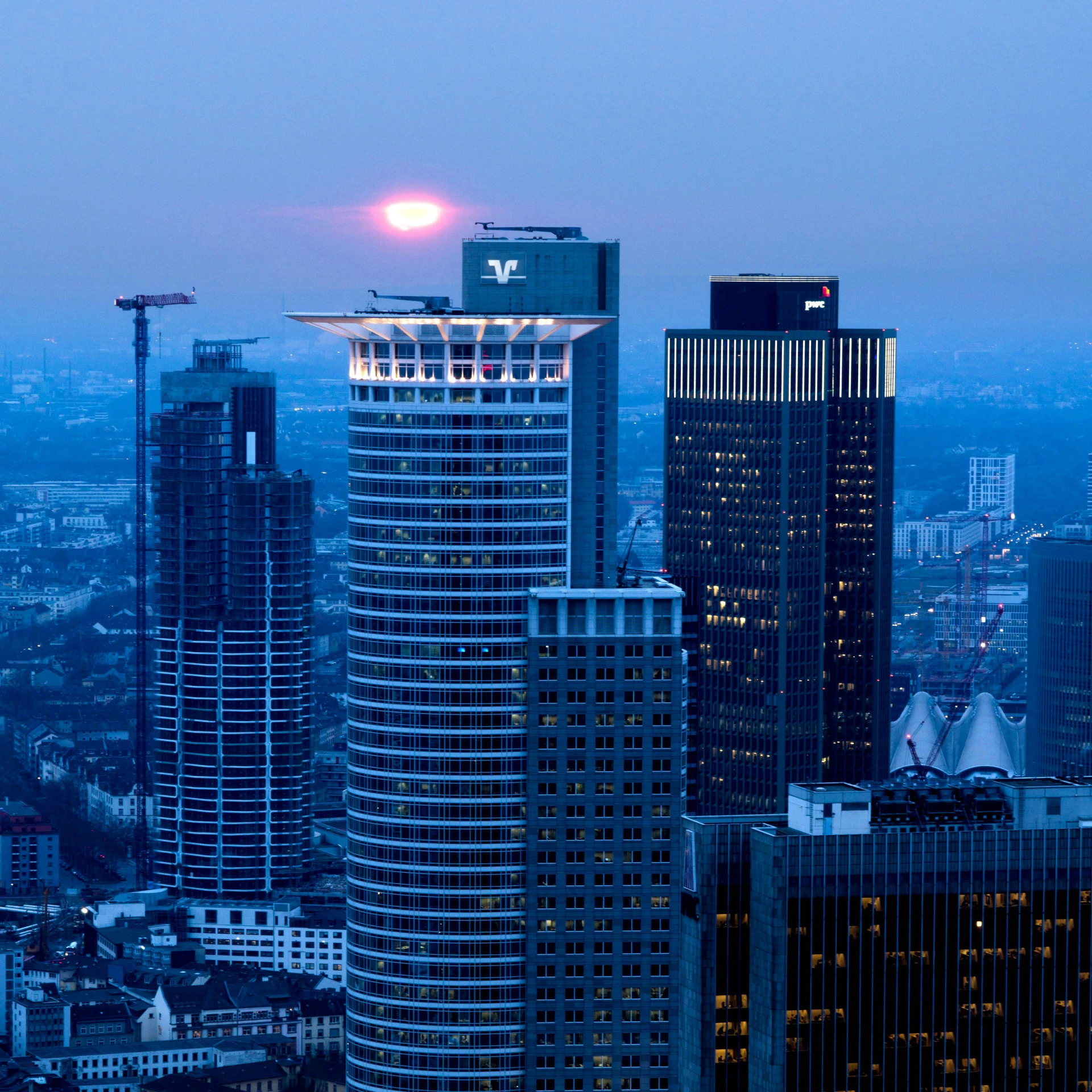 several tall buildings in front of a bright sky