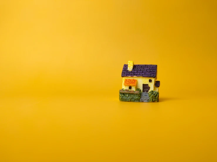 a small miniature yellow house sitting in front of a yellow wall