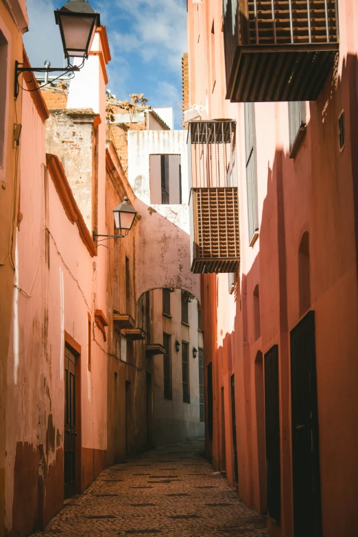 a narrow street with lots of buildings and buildings painted pink