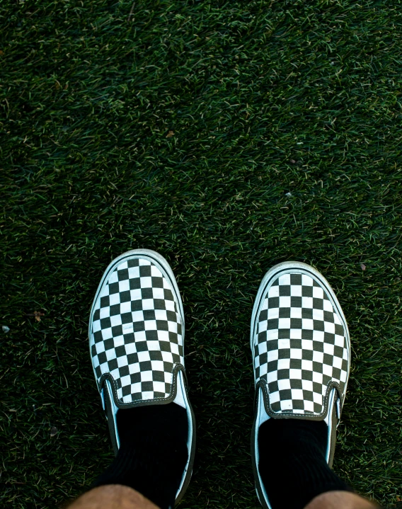 someone wearing black and white checkered slip on their shoes