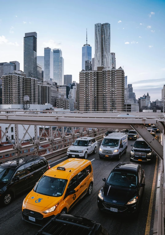 a city view from a bridge, with several vehicles traveling down it